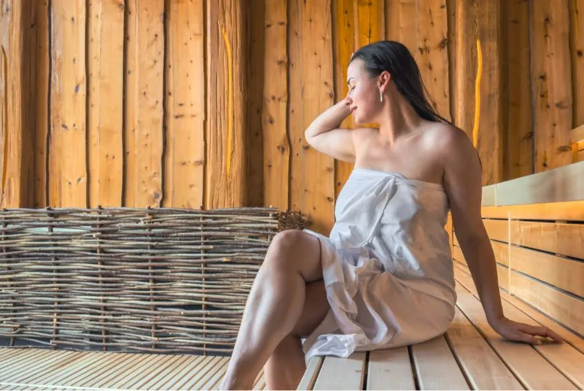 Frau entspannt in klassischer Outdoor Sauna aus Holz mit natürlicher Wellnessatmosphäre