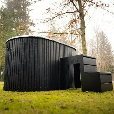 Aiste Grand Eisbadewanne im Garten mit schwarzer Holzoptik und integrierter Einstiegstreppe