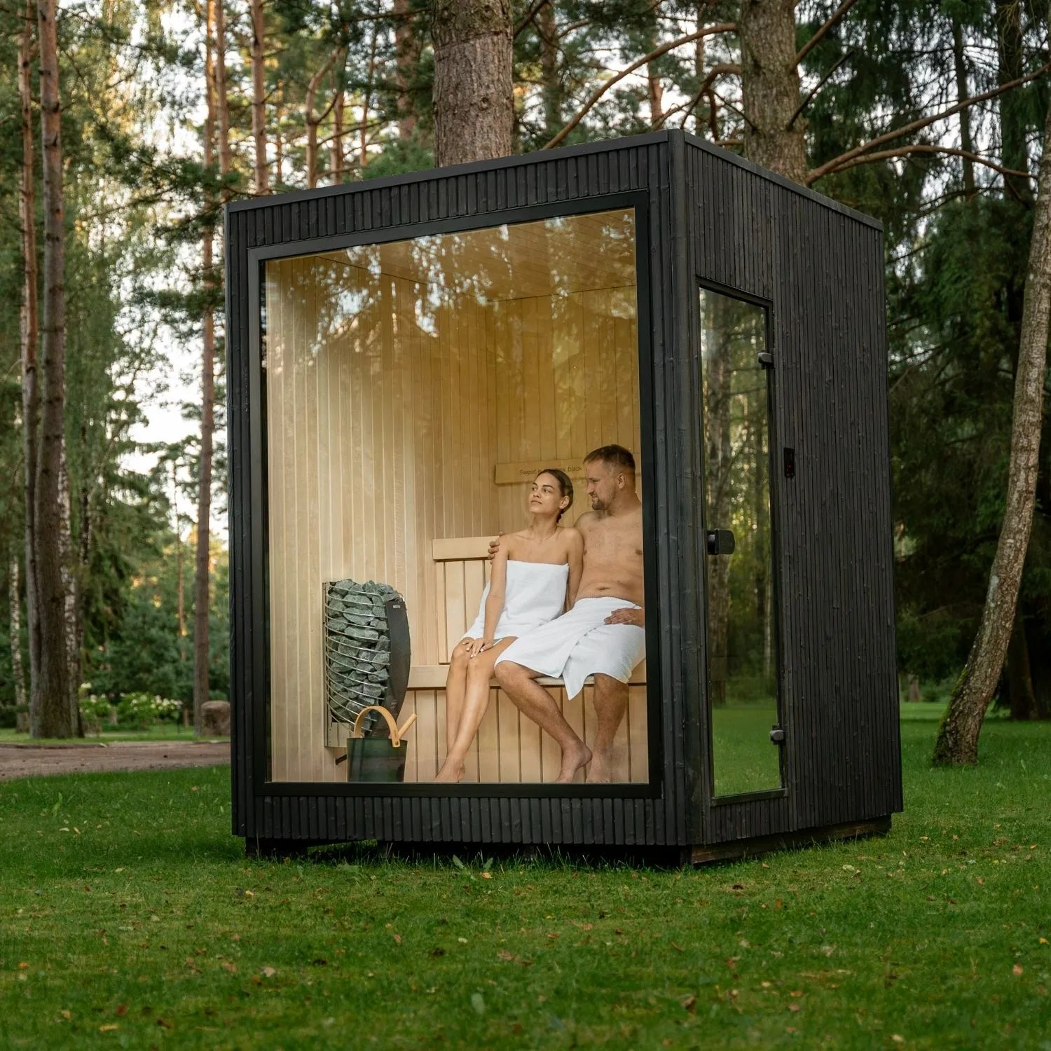 Moderne Gartensauna Jonas Classic mit großzügiger Glasfront im Grünen – hochwertige Holzverarbeitung und klare Architektur für entspannte Wellnessmomente im eigenen Garten.