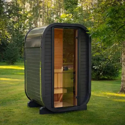 Moderne schwarze Außensauna mit abgerundetem Design und Glastür, platziert auf einer grünen Rasenfläche im Garten.