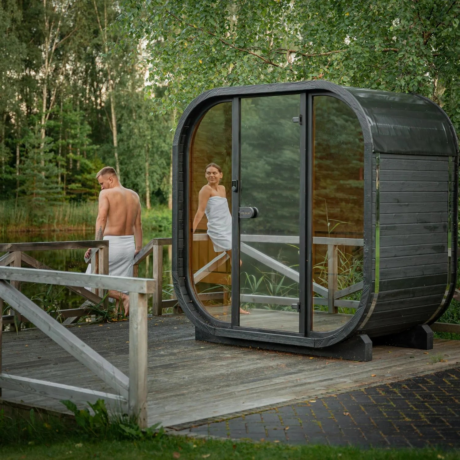 Moderne Gartensauna Ula Mini mit großzügiger Glasfront im Grünen – hochwertige Holzverarbeitung und klare Architektur für entspannte Wellnessmomente im eigenen Garten.