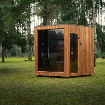 Jonas Classic Outdoor Sauna in Teak mit großer Glasfront auf einer grünen Rasenfläche.